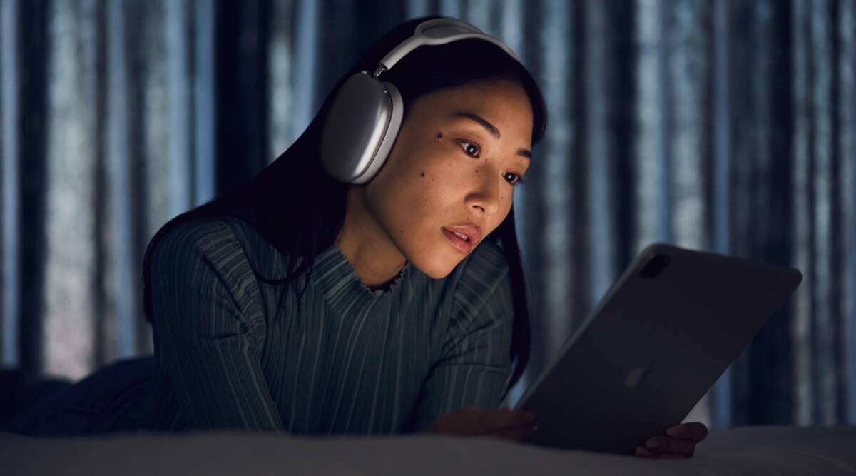 Apple teria levado quatro anos para terminar o design dos novos AirPods Max - imagem mostra mulher utilizando um iPad enquanto usa o headphone da empresa