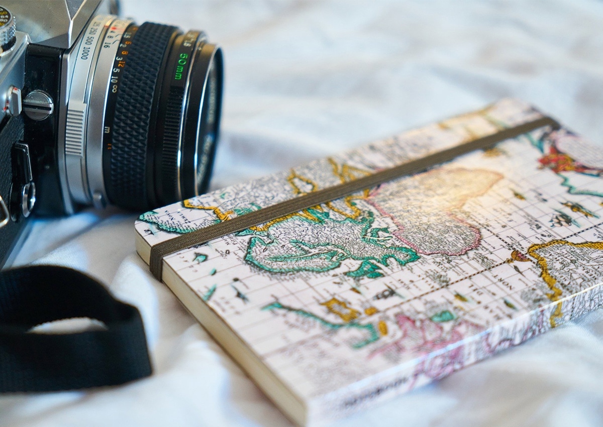 Uma câmera fotográfica com um caderno de desenho com um mapa na capa