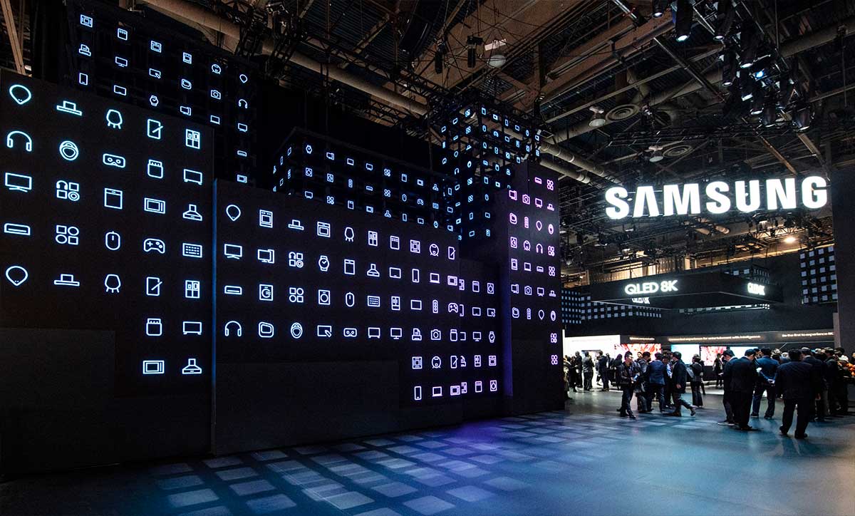 Imagem mostra estande da Samung em uma das edições da CES - é possível ver painéis de led mostrando ícones da empresa ao lado de um letreiro escrito Samsung - em 2021 empresa apresentará suas novidades em 11 de janeiro