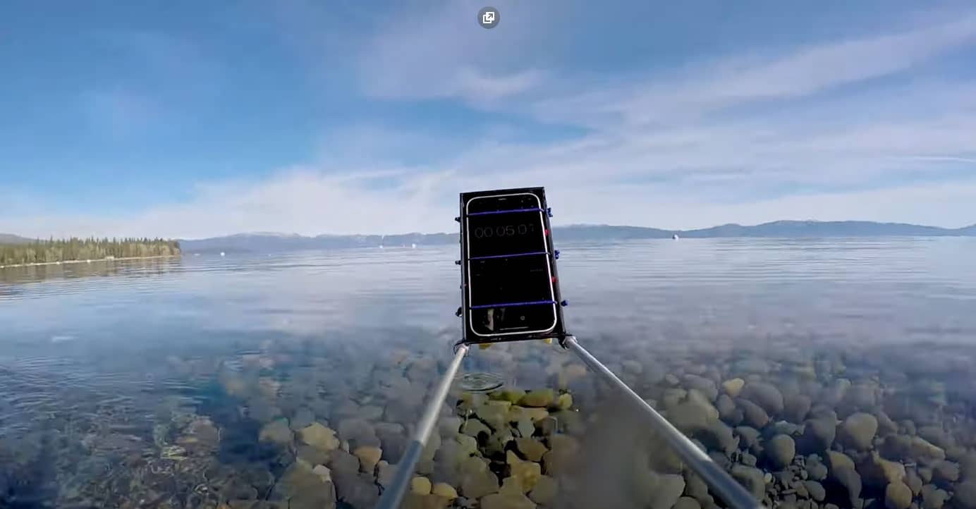iPhone 12 amarrado a um dispositivo com duas hastes de metal se prepara para mergulhar no lago