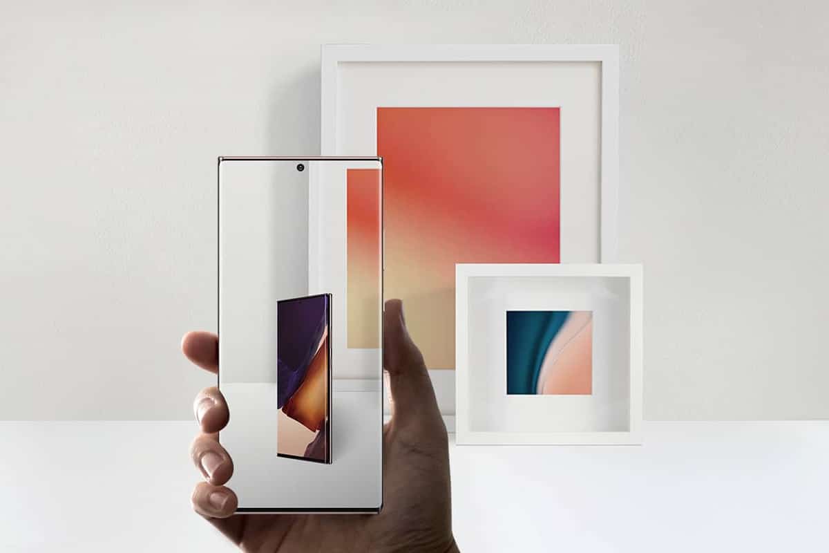 Galaxy Note 20 segurado com uma mão e com dois quadros ao fundo