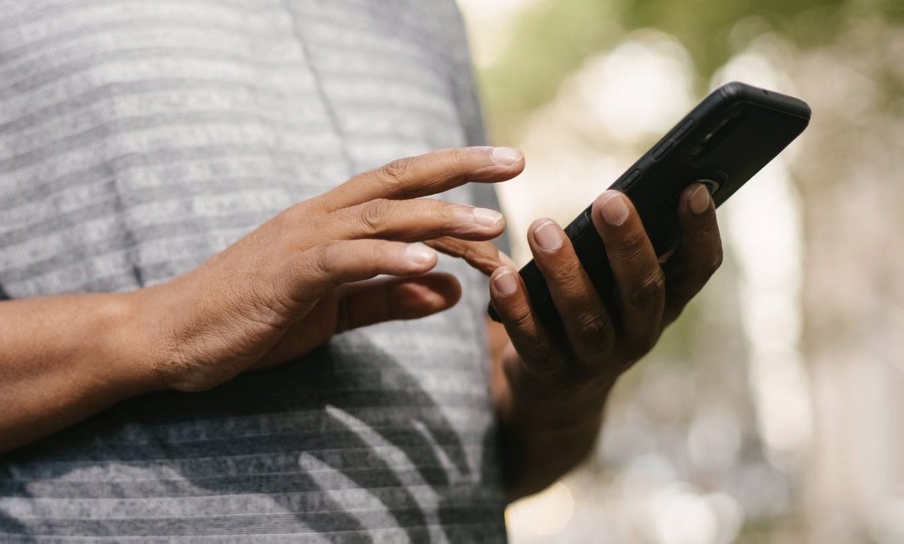 Homem teclando em celular, android teve problemas no envio de SMS