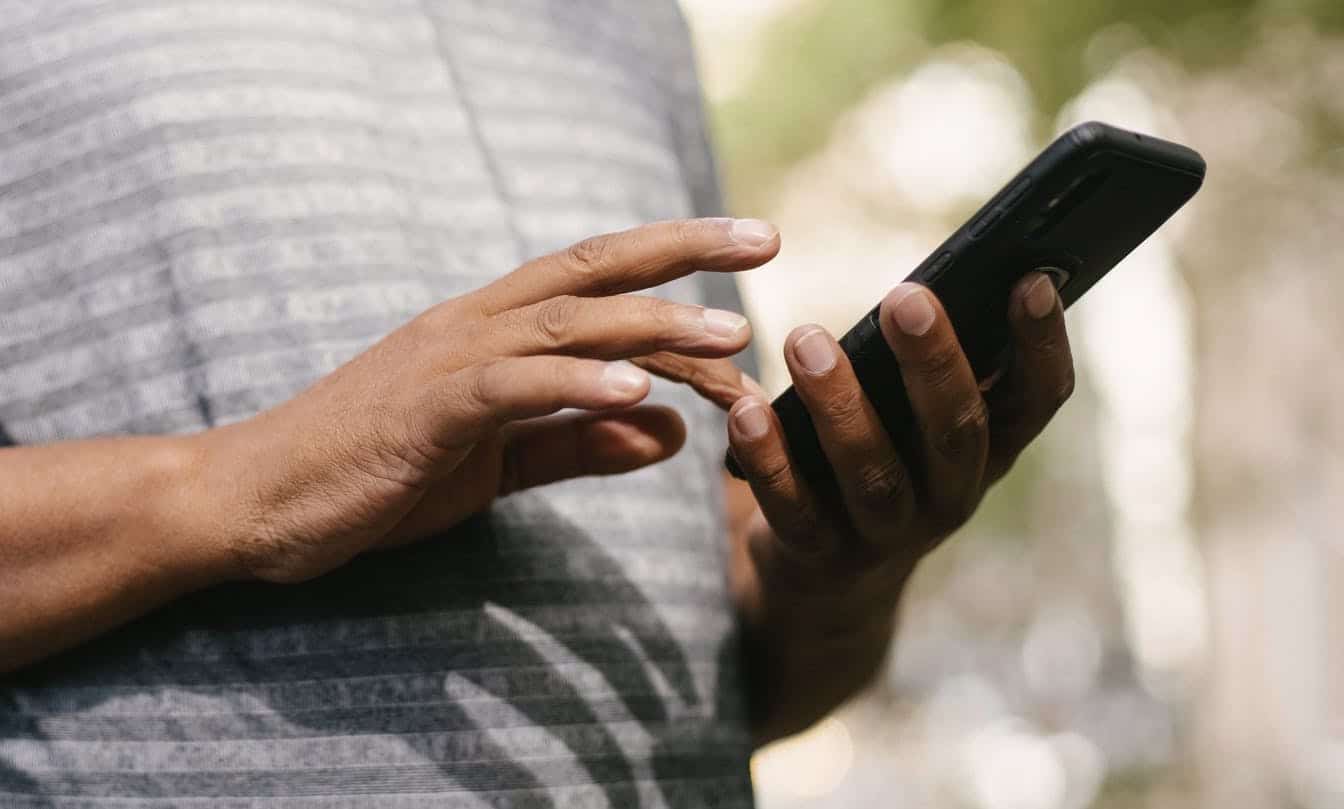 Homem teclando em celular, android teve problemas no envio de SMS