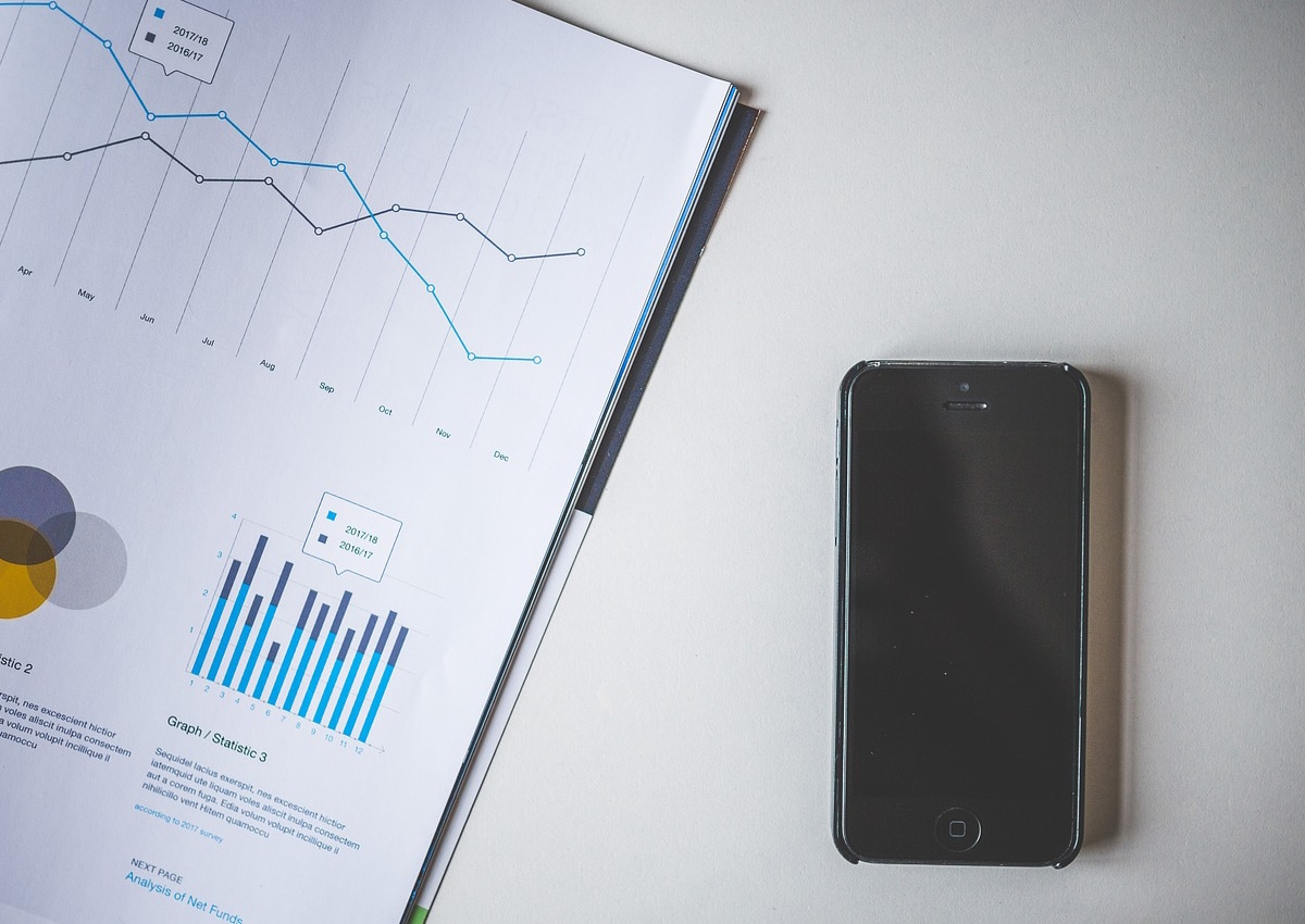 Gráfico do mercado desenhado em um papel e smartphone ao lado