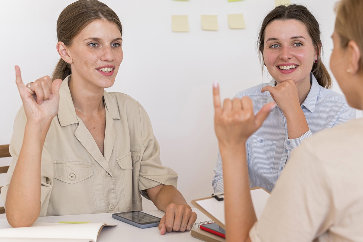 três mulheres se comunicando em linguagem de sinais