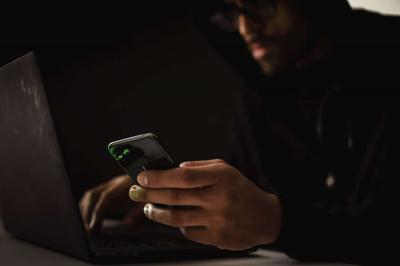 Hacker usando computador e celular
