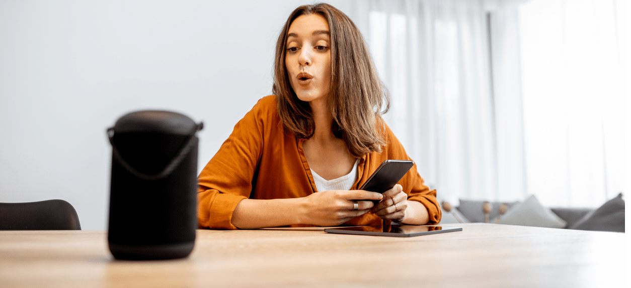 Mulher jovem controlando um smart speaker com comando de voz