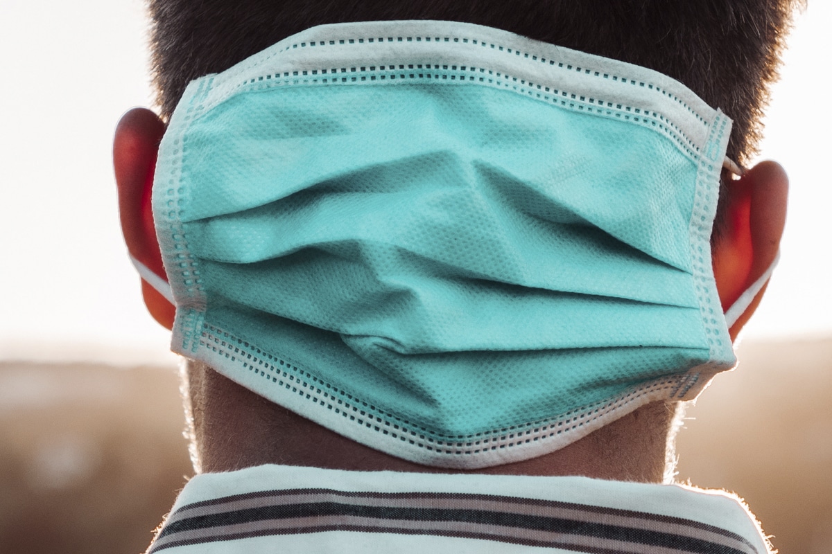 homem utilizando máscara facial na nuca