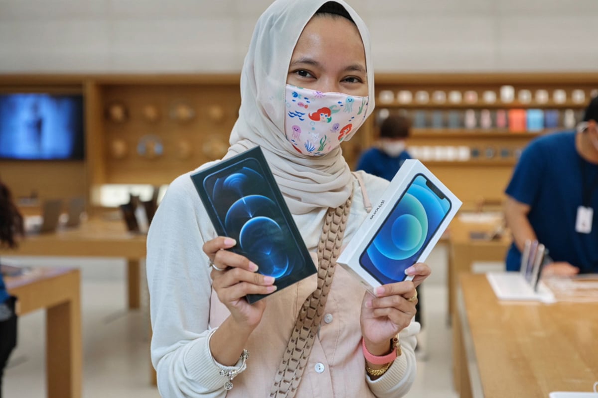 moça de máscara e véu segurando duas caixas de iPhones 12