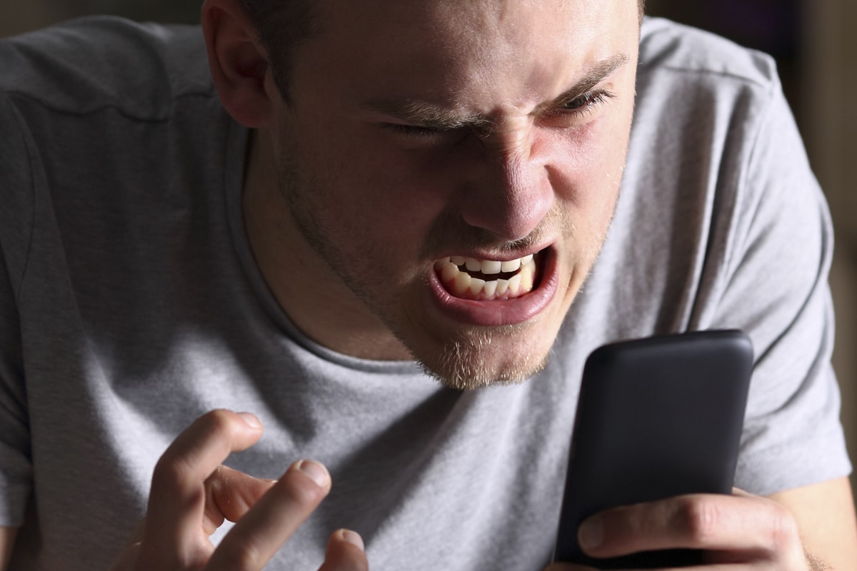 homem enfurecido olhando para o celular