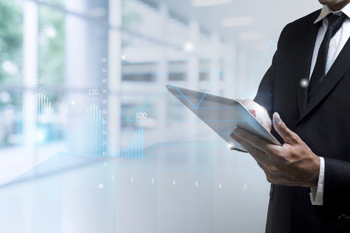 homem de terno segurando um laptop ilustrando uma medição de indicadores e um gráfico em marca d'água