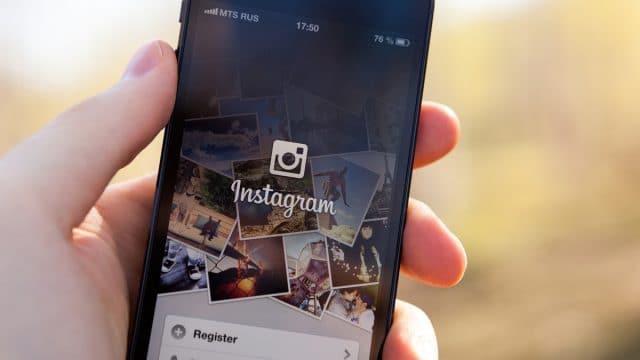 Pessoa com o celular na mão usando o Instagram