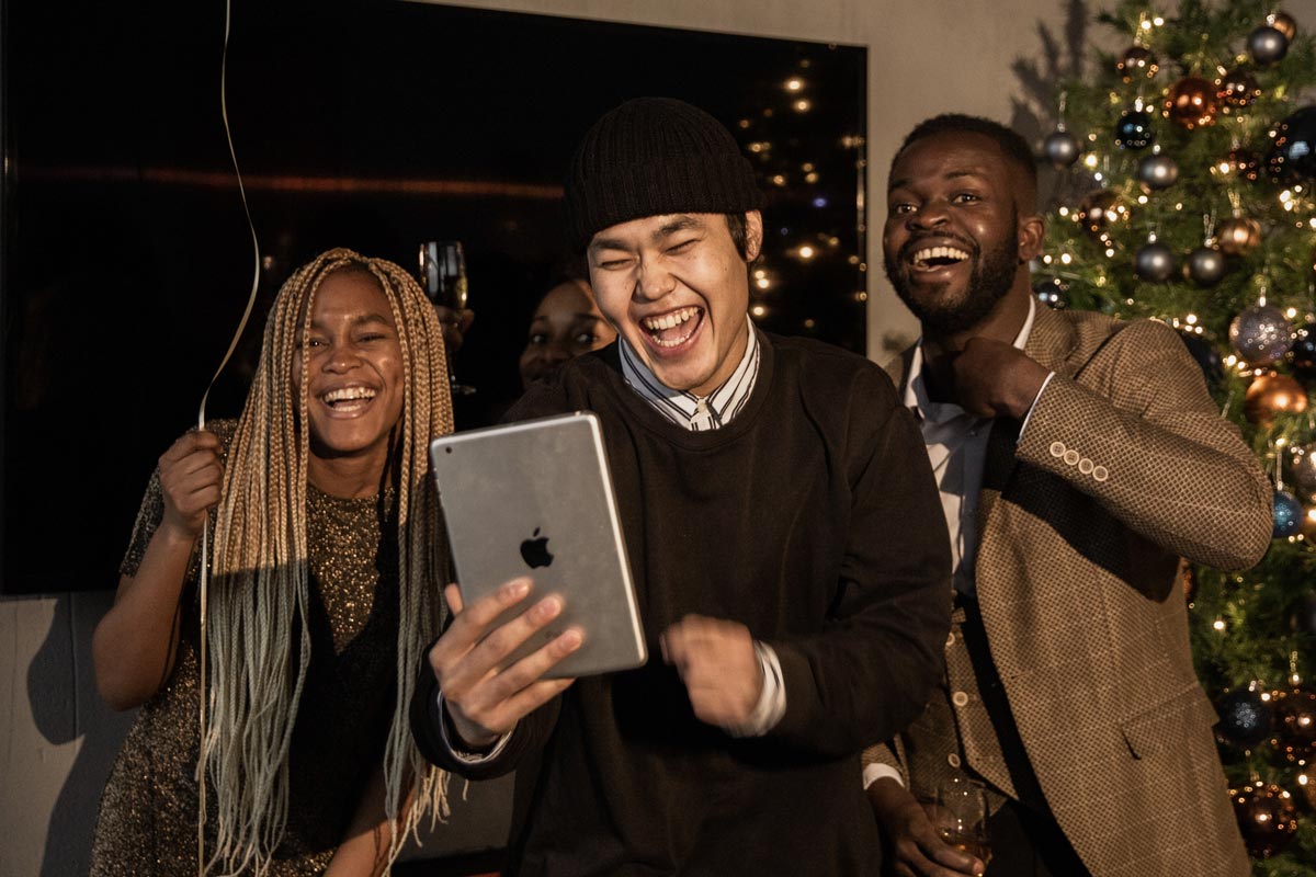 três pessoas rindo enquanto fazem chamada de vídeo