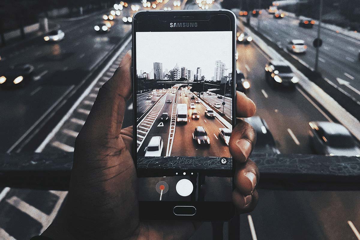 mão com celular fotografando trânsito na estrada