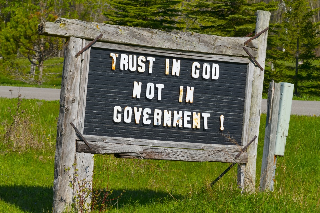 placa com os dizeres em inglês: acredite em Deus e não no governo