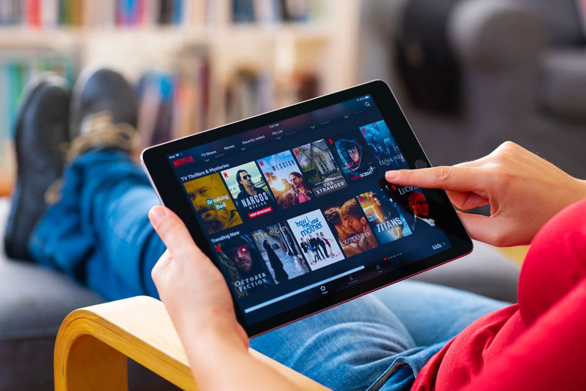 pessoa segurando tablet com catálogo de filmes da netflix