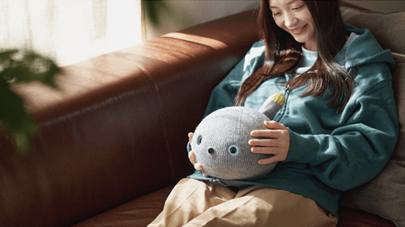 Imagem mostra uma moça acariciando Nicobo, o gato-robô da Panasonic, sucesso de vendas em crowfunding