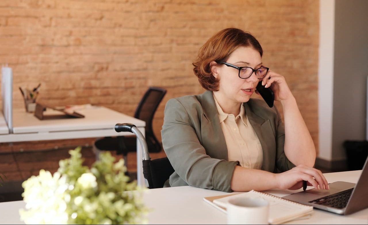 mulher ao telefone enquanto mexe no computador