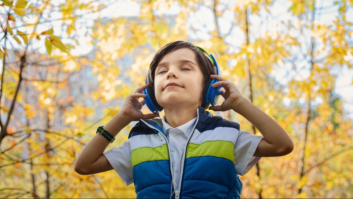 Menino ouvindo música com fones de ouvido no meio da floresta