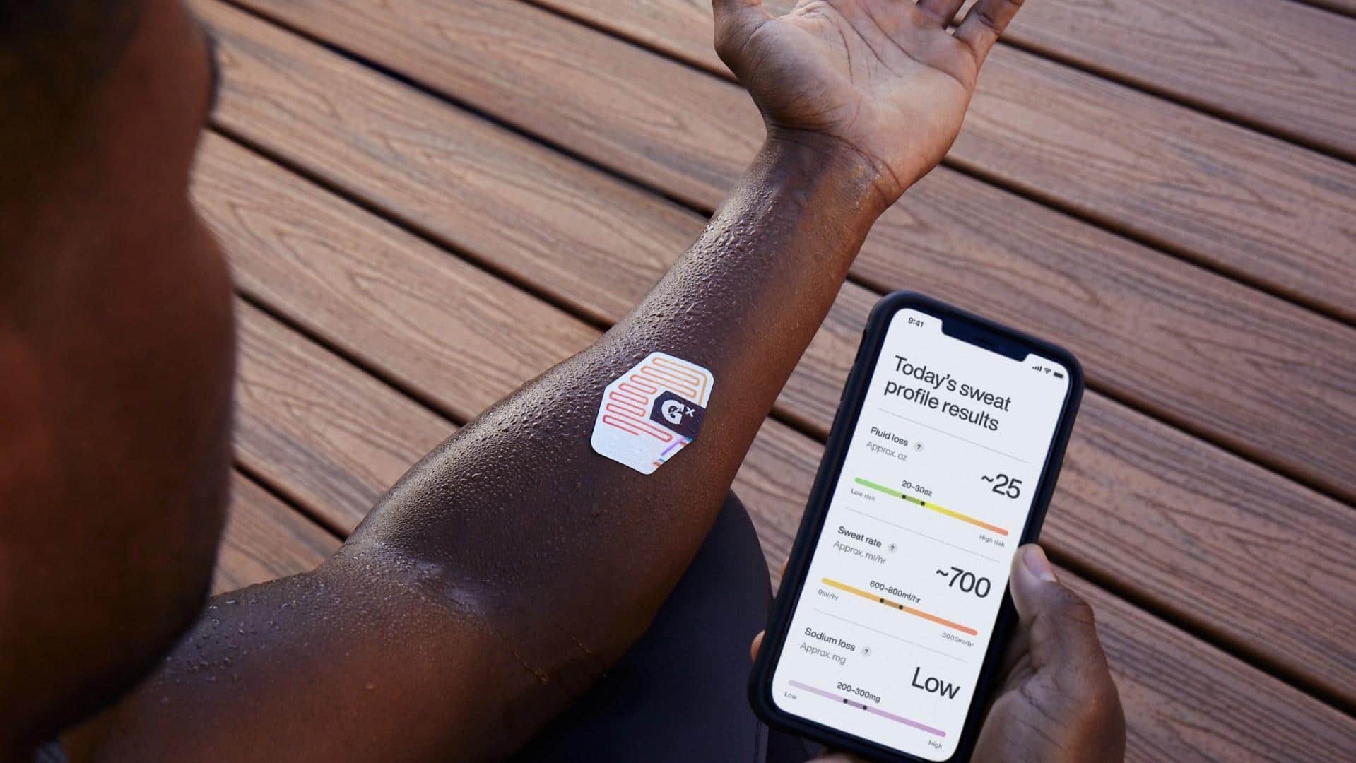 Braço esquerdo com o patch de suor da Gatorade. Há também celular iPhone com o Gx App exibindo as informações de suor