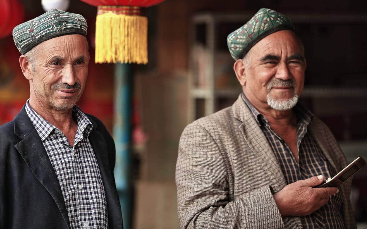 dois homens da minoria uigur na China, um deles usando celular