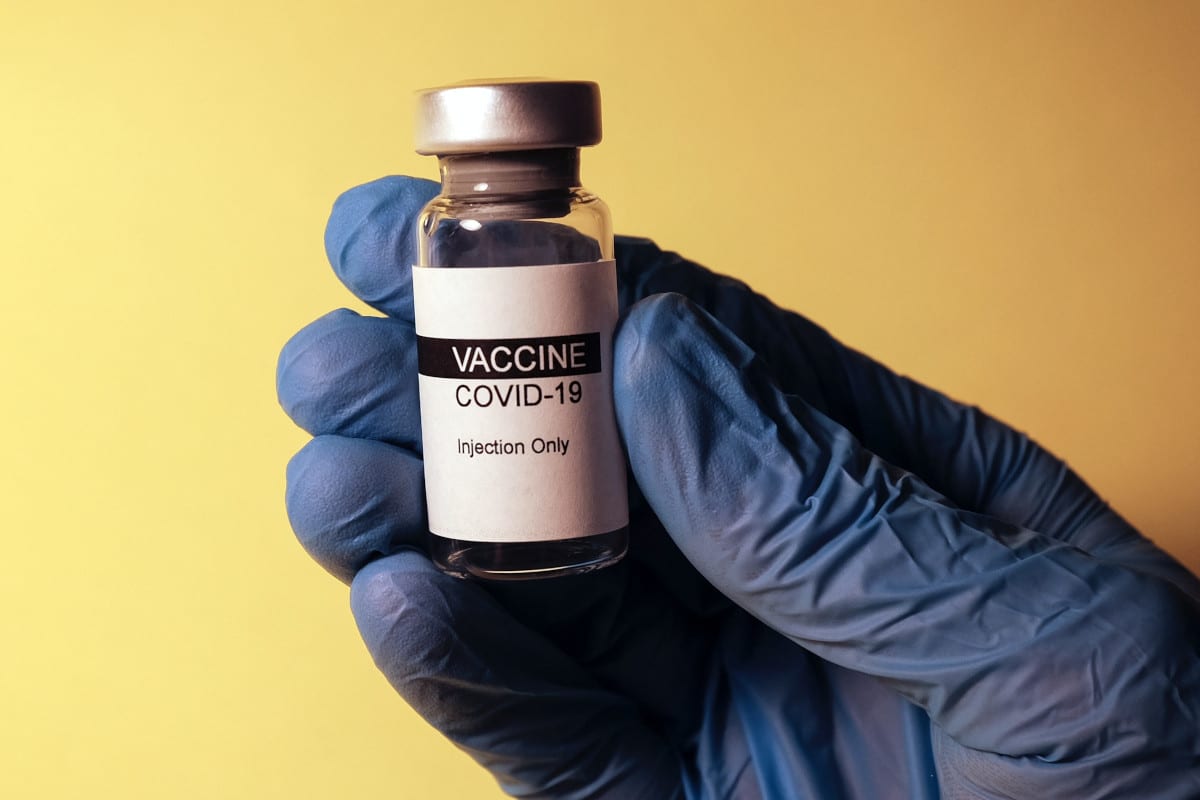 Imagem de uma suposta vacina contra Covid segurada por mão com luva