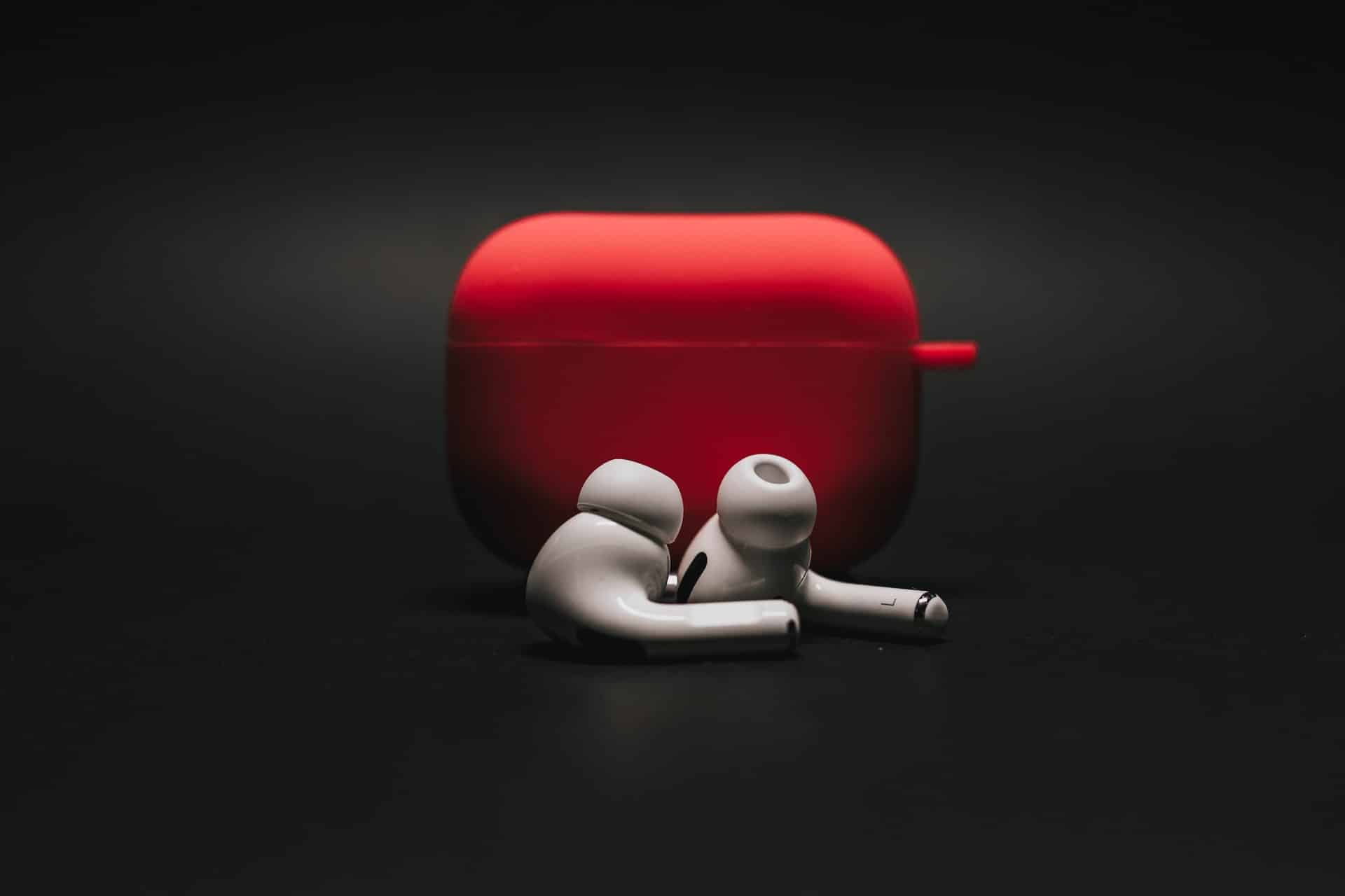 A imagem mostra um par de AirPods Pro posicionados na frente de um case vermelho