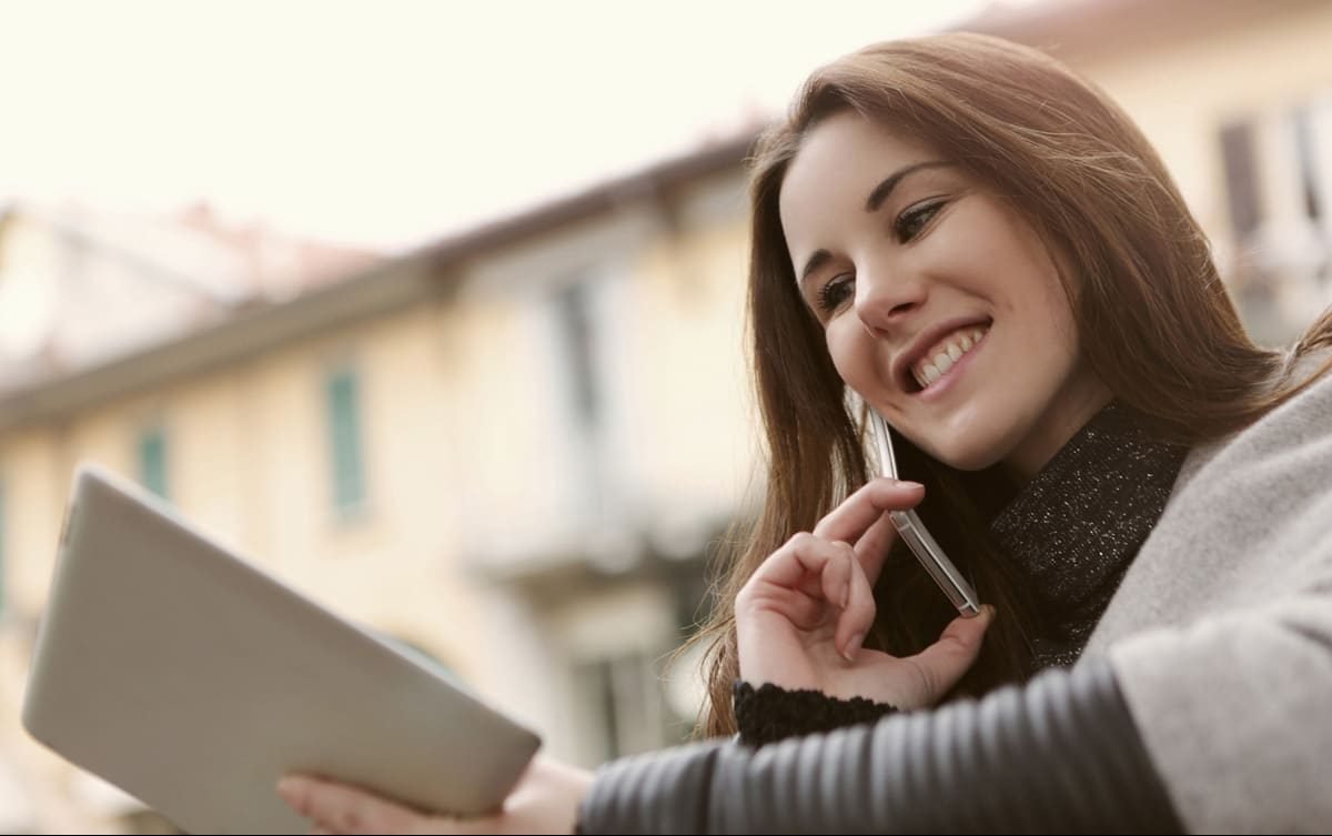 mulher falando no telefone enquanto olha tablet