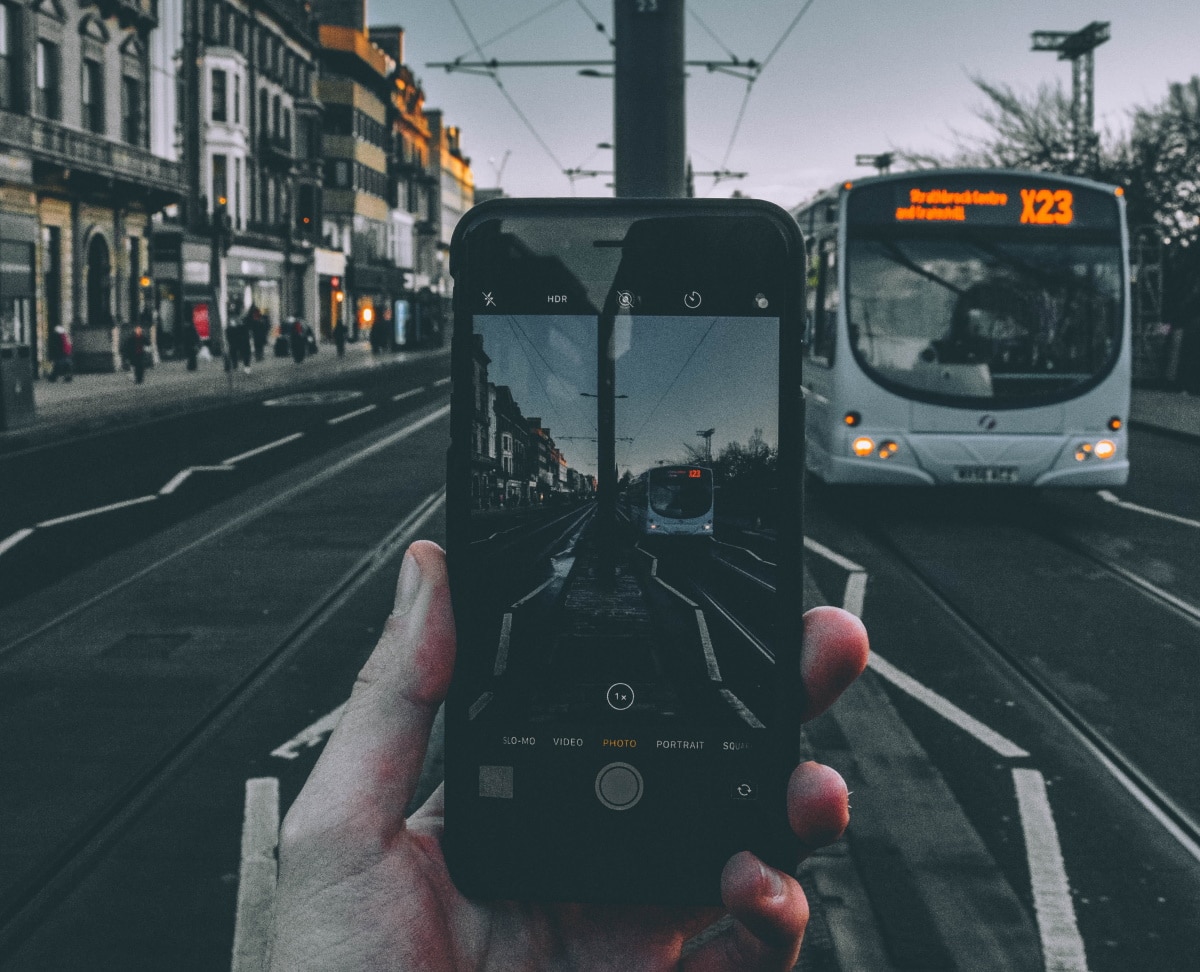 Imagem mostra pessoa segurando celular e esperando ônibus. Roubo e furto de celulares, principalmente no transporte público, aumentaram procura por seguro de celular