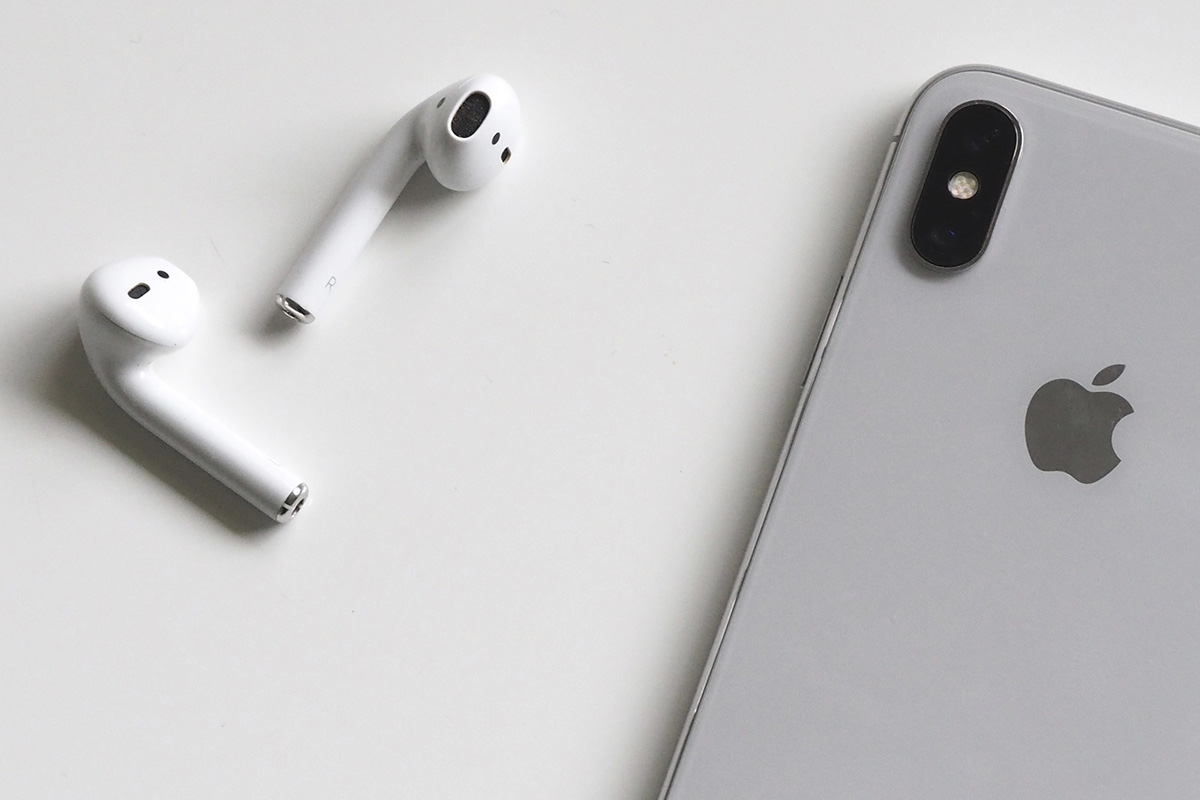 fones de ouvido brancos e um iPhone mais prateado