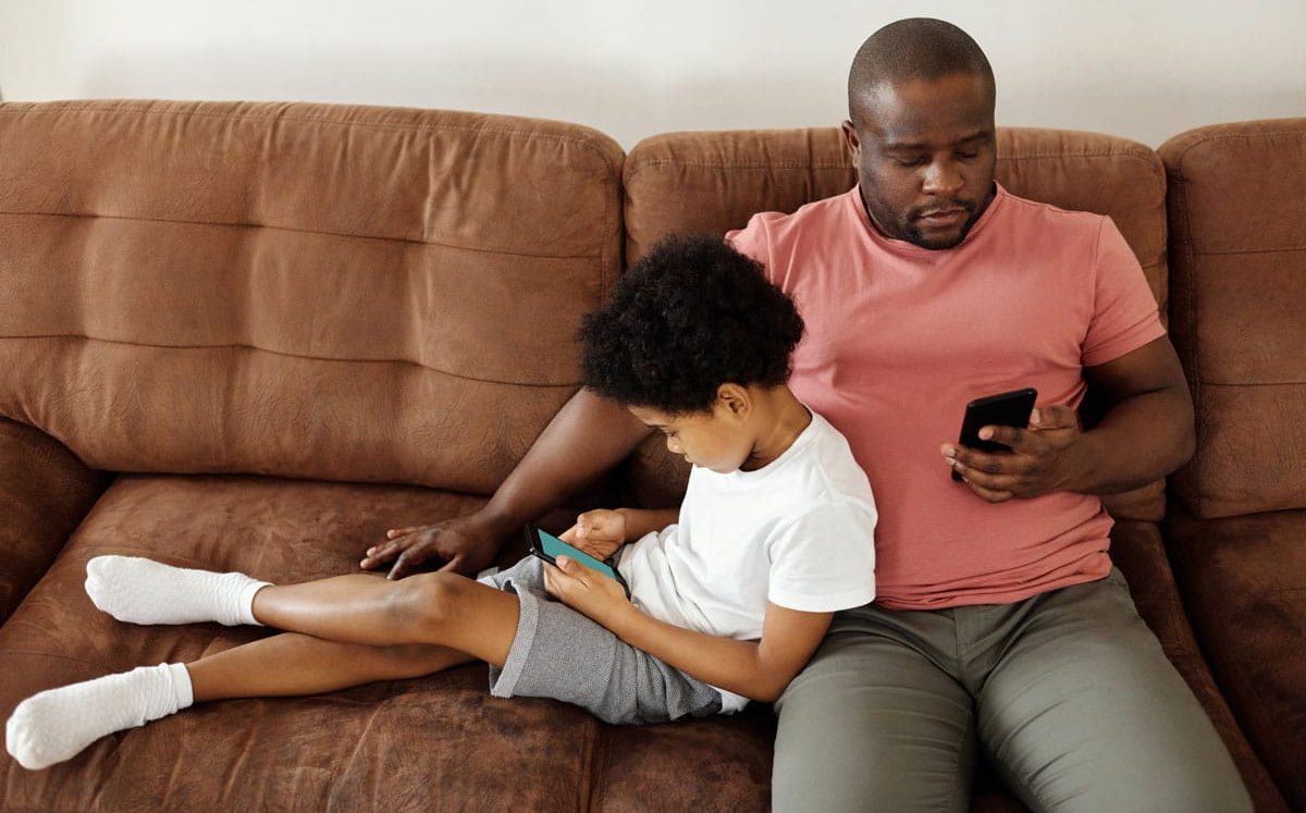 pai e filho usando celular no sofá