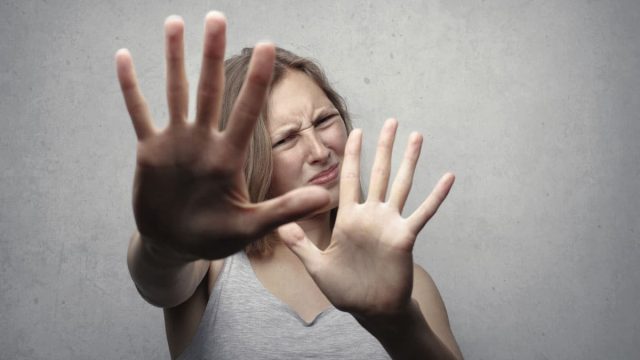 Mulher estendendo a mão em desaprovação mantendo distância