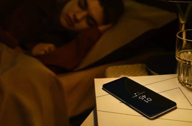pessoa dormindo com um celular Oppo F19 Pro+ no criado mudo e um copo de agua ao lado