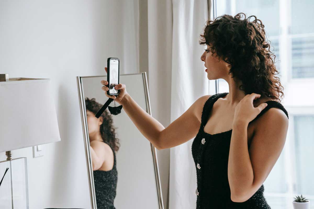 mulher provando roupa na frente de celular