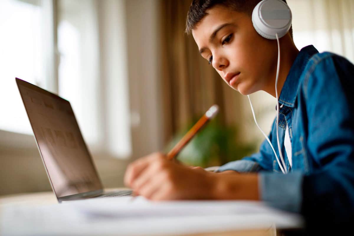 Criança estudando de fone na frente do tablet