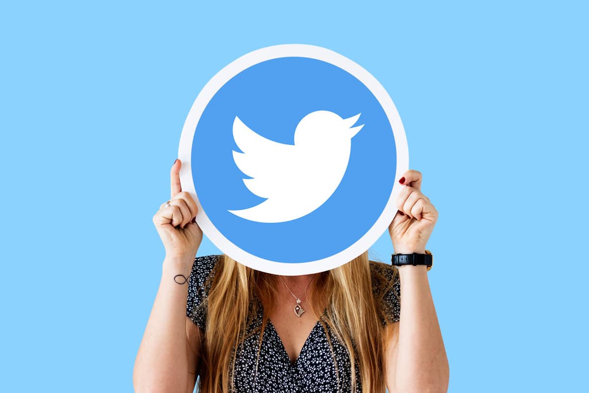 mulher escondendo o rosto atrás de logo do Twitter