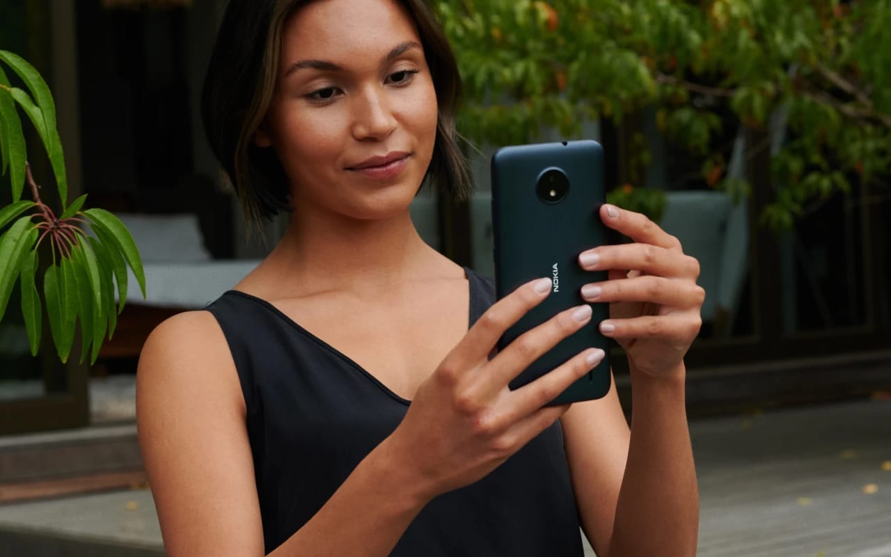 moça segurando e olhando para a tela do Nokia C10, da Série C da empresa