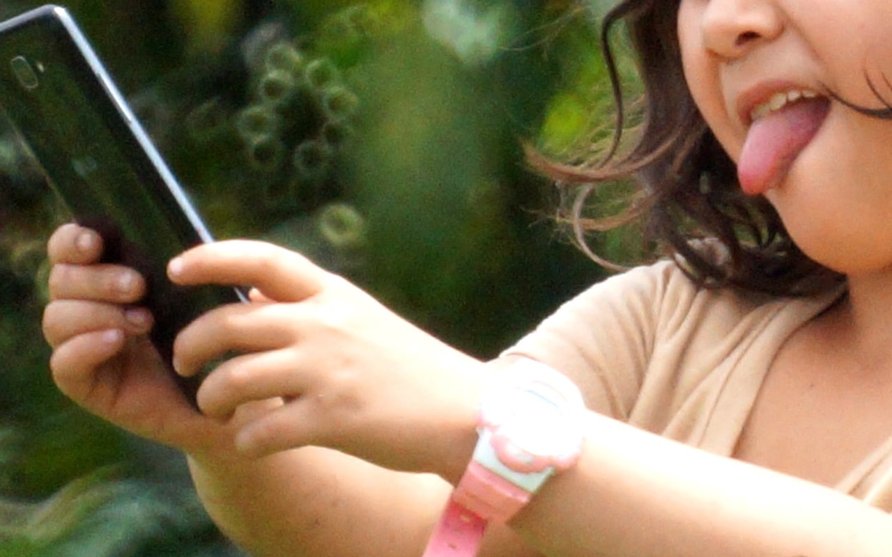 criança mexendo em um celular, foco da preocupação dos grupos dos direitos das crianças com relação ao Instagram