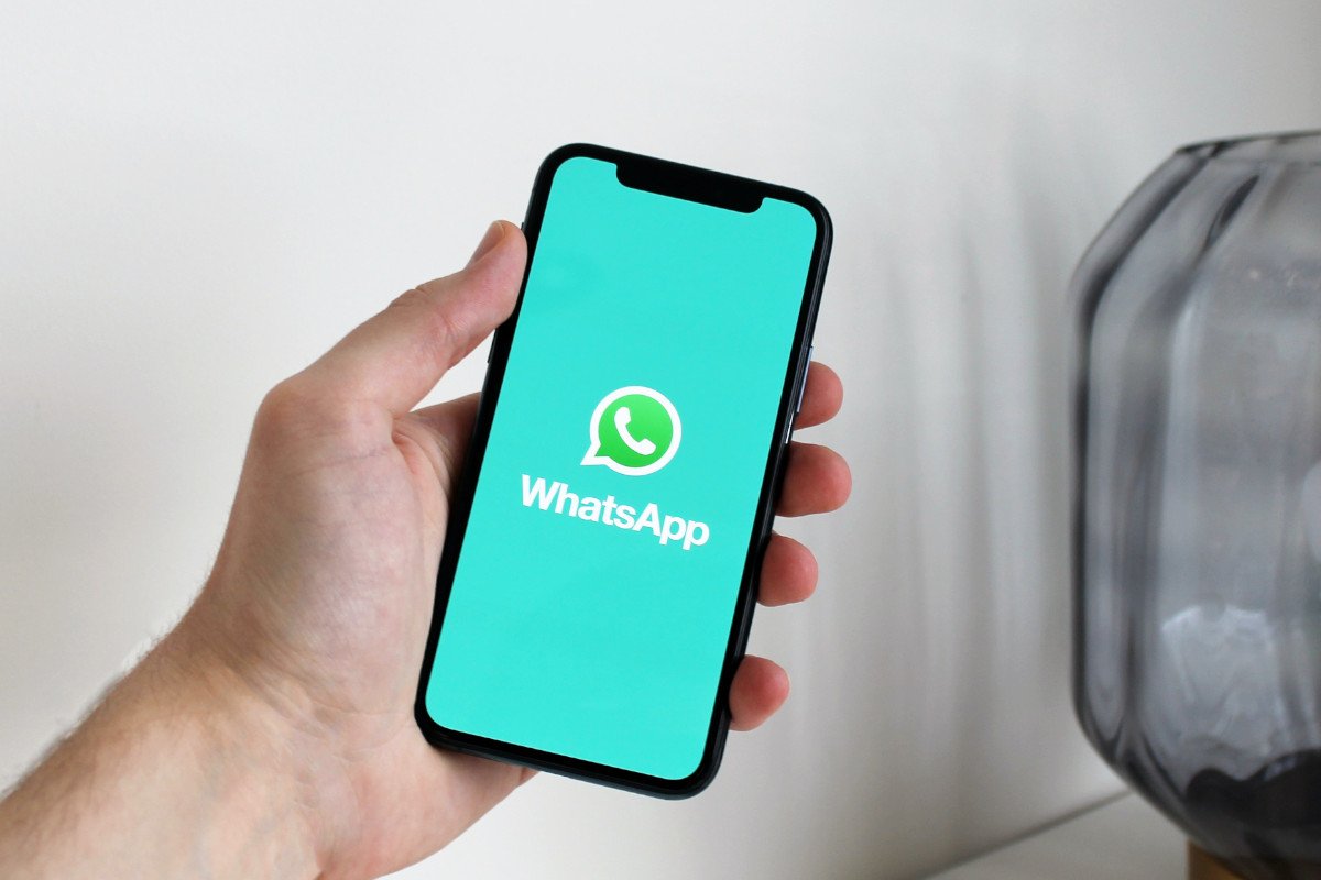 Mão masculina segurando celular com Whatsapp na tela