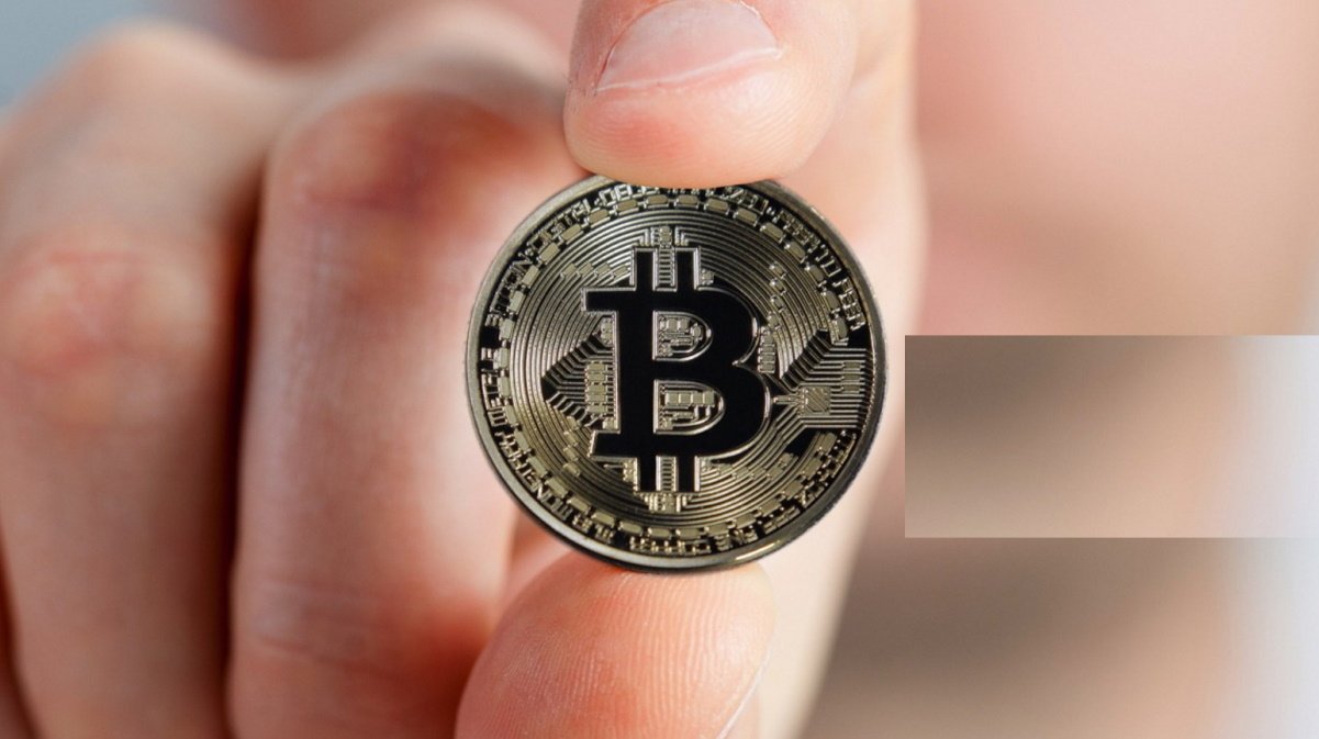 Imagem mostra mão segurando bitcoin, representando que a Coinbase agora aceita compra em criptomoedas nos EUA