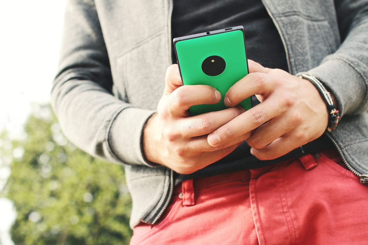 Homem utilizando um celular Nokia verde visto de baixo