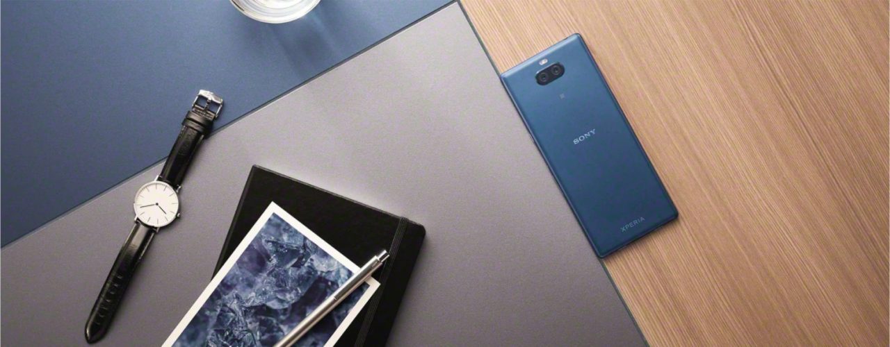 Montagem com uma mesa com dispositivos eletrônicos em cima, incluindo um smartphone Sony Xperia