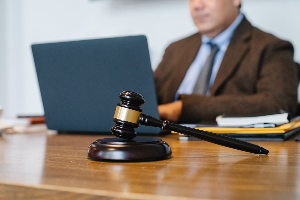 Homem utilizando notebook com martelo de tribunal na frente