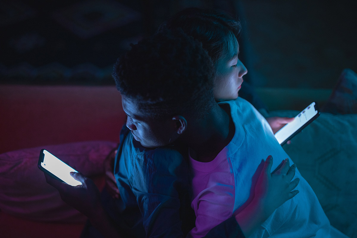 casal abraçado usando o celular pelas cotas um do outro