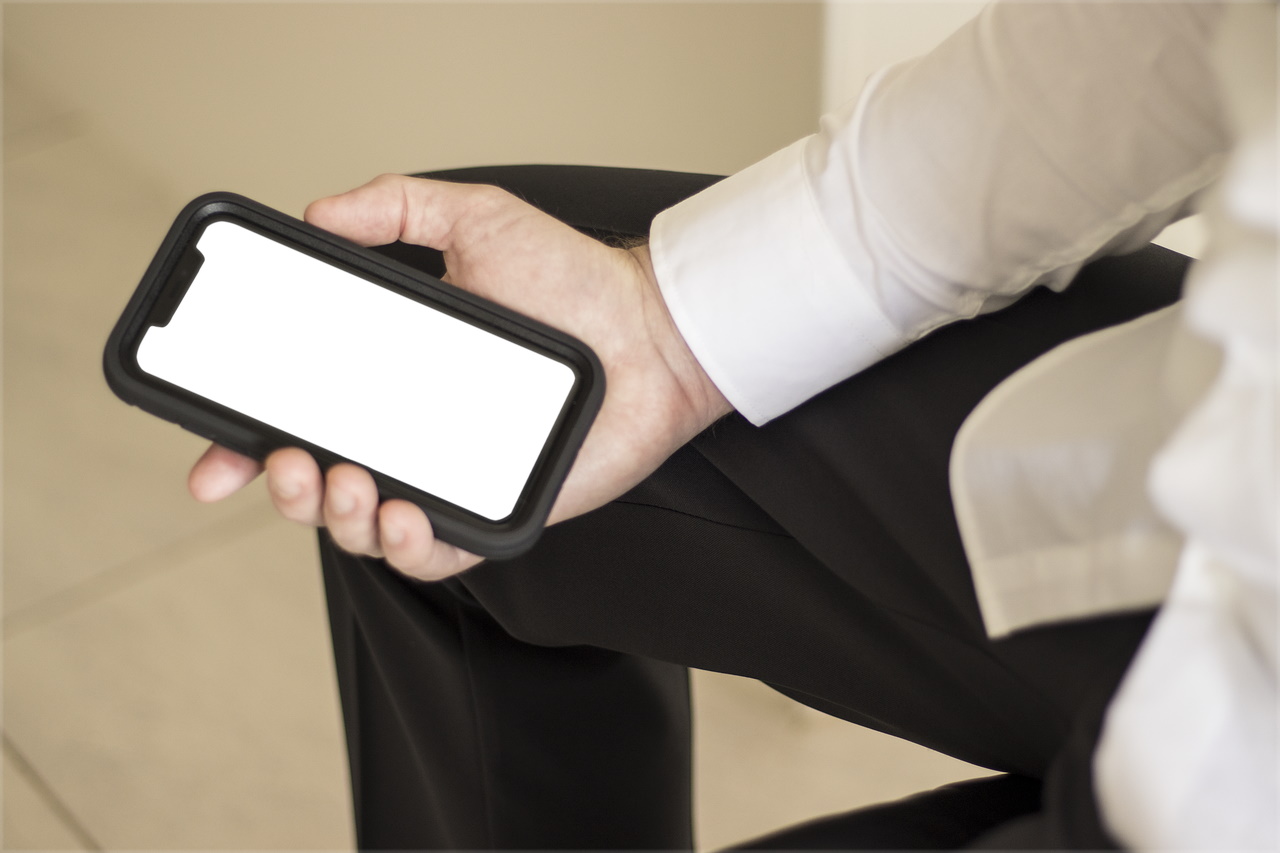 Imagem mostra homem segurando um iPhone com a tela em branco e sem botões. Apple estaria trabalhando em futuros dispositivos sem botões