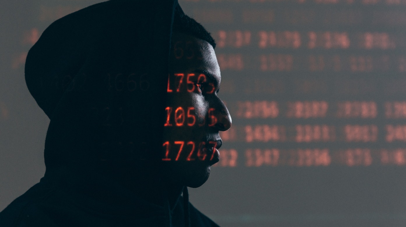 Imagem mostra homem encapuzado e uma série de números ao fundo e passando por seu rosto, simbolizando falha de segurança no WhatsApp que pode permitir o roubo da sua conta