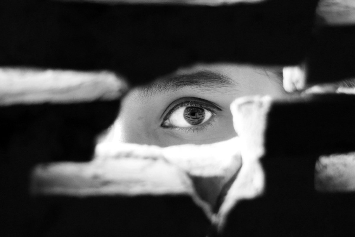 olho vigiando a pessoa por buraco