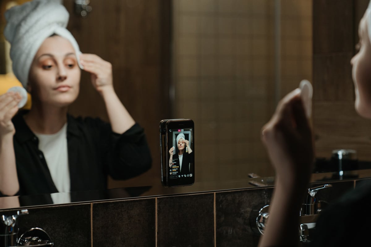 criadora de conteúdo gravando vídeo com celular grudado no espelho enquanto se maquia