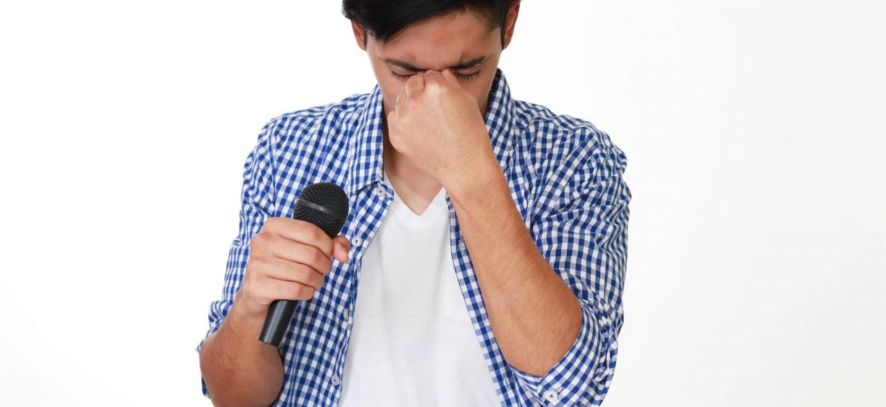 homem preocupado segurando um microfone para ilustrar os moderadores do Facebook sendo orientados a cantar em karaokê para lidarem com o trabalho