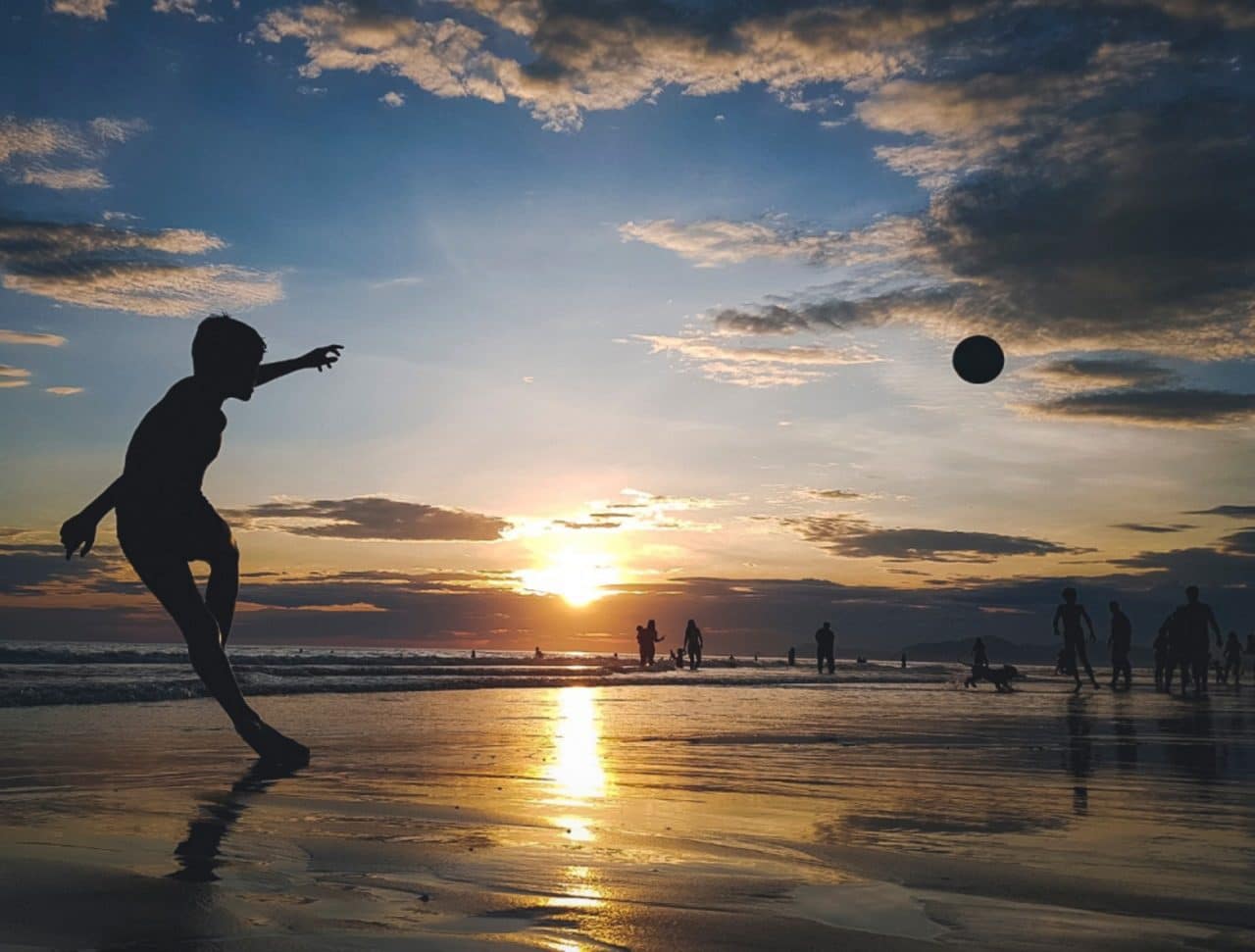 Imagem mostra garoto chutando bola na praia, mostrando como é possível tirar boas fotos com o celular